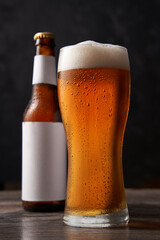 Bottle and glass of beer on black background.