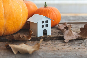 Autumnal Background. Toy house and pumpkin on wooden background. Thanksgiving banner copy space....