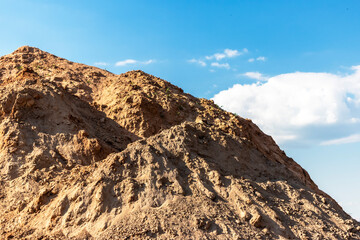 Heap of earth sand and clay at the construction site against the sky. Earthworks at the construction site.