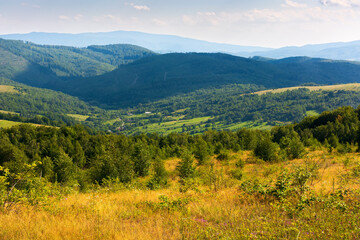 Obraz premium mountain scenery on an idyllic summer day. countryside landscape of capathian alps with fresh green meadows an forested hills. village in the distant valley. clouds on the blue sky in afternoon light