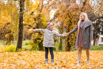 Mother and daughter in autumn yellow park.