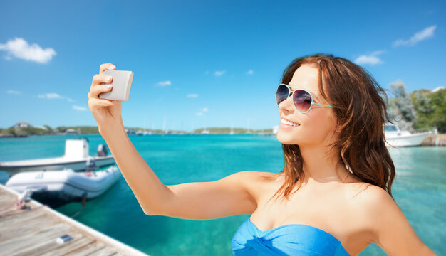 travel, tourism and summer vacation concept - beautiful woman with smartphone taking selfie over wooden pier and boat on tropical beach background in french polynesia