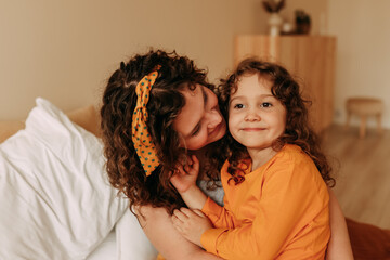 Portrait Of Happy Smiling Curly-haired Mom And Daughter On Mother's Day At Home