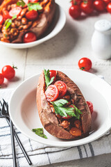 Baked sweet potato stuffed with beans in tomato sauce. Vegan recipe concept.