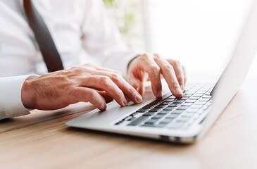 Businessman using laptop computer, hands typing keyboard at office desk