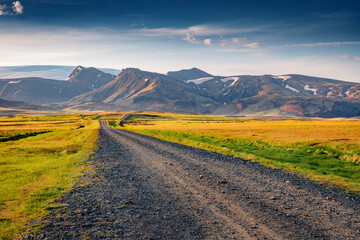 Typical icelandic landscape of empty country road with volcanic mountains on background. Colorful summer scene of south coast of Iceland, Europe. Traveling concept background. - obrazy, fototapety, plakaty