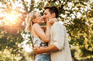 summer holidays, love and people concept - happy young couple kissing and hugging outdoors