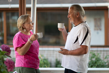 Retirement. Mature couple drinking coffee on porch. Two senior man and woman drinking coffee and smiling or discussing future plan after retire.