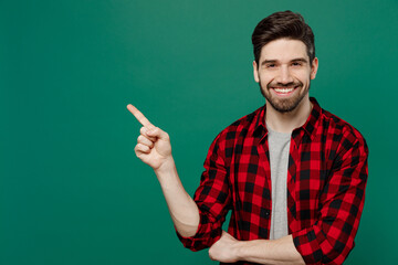 Young happy smiling man he 20s wear red shirt grey t-shirt indicate point index finger aside on workspace area mock up isolated on plain dark green background studio portrait People lifestyle concept.