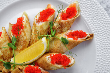 Pancakes with salmon, cream cheese and Tobiko caviar. on a white background