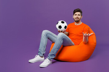 Full body sad young fan man he wear orange t-shirt cheer up support football sport team hold soccer...
