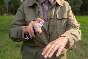 health care, protection and people concept - woman spraying insect repellent or bug spray to her...