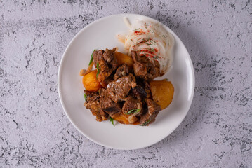 kuyrdak, roast, fried potatoes with meat. on a light concrete background
