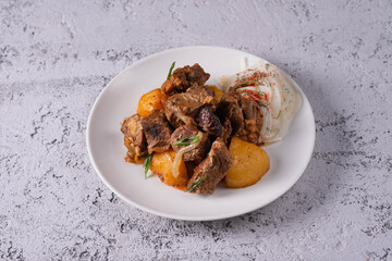 kuyrdak, roast, fried potatoes with meat. on a light concrete background