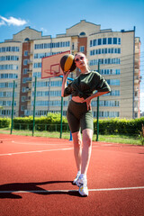 Obraz premium in tight-fitting sports uniform, a woman is playing basketball in an open-air stadium.