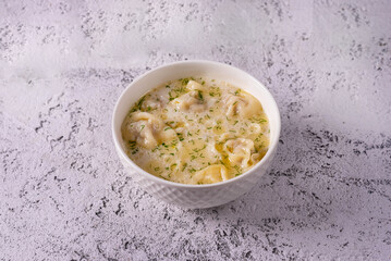 dumplings with broth and sour cream. on light concrete