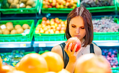 Fototapeta na wymiar young woman in supermarket choosing pomegranate fruits