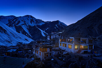 Rumbak village in the valley, Hemis NP, Ladakh in India. Night winter landspape from Himalayas mountain. Buildings with light on the evening. Traveling in Ladakh, hills with snow.