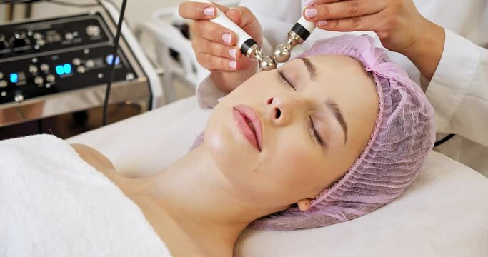 Beautiful woman receiving facial microcurrent treatment at spa salon. Beautician using electrical impulses for facial procedures. Woman in spa salon. Woman in a spa salon on cosmetic procedures.