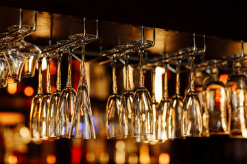 Empty clean upside-down crystal wine glasses hanging from the bar in luxury restaurant. Selective...