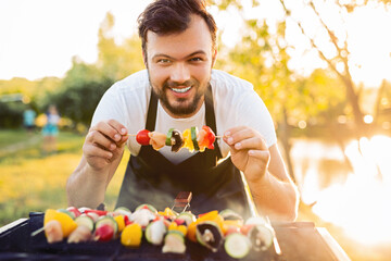 Merry chef showing skewer over grill