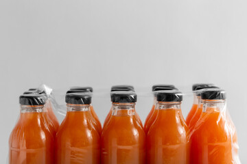 storage, drinks and packaging concept - close up of pack of glass bottles with fruit or vegetable...