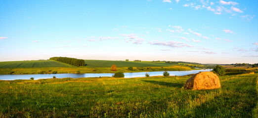 Summer rural landscape with hay bale and calm river