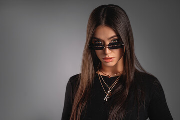 Beautiful young lady in a black turtleneck with massive jewelry and extraordinary sunglasses. Refined taste. Elegance. Sexy. Copy space