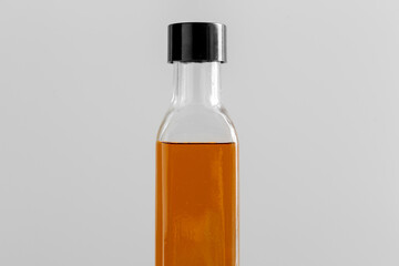 healthy eating, food and culinary concept - close up of olive oil in glass bottle on grey background