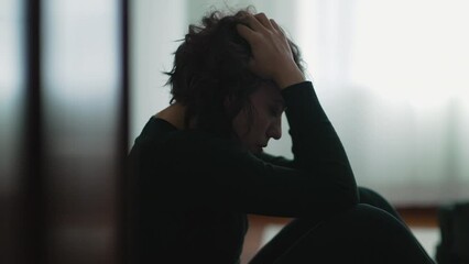 Depressed woman sitting on floor covering face with hands in despair - Powered by Adobe