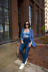 brunette girl in a blue jacket and jeans walks through the city streets