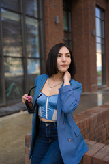 brunette girl in a blue jacket and jeans walks through the city streets