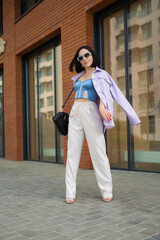 brunette girl walks in the city. blue corsage, lilac jacket