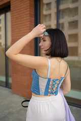 brunette girl walks in the city. blue corsage, lilac jacket