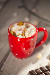 Hot chocolate with marshmallow in red dotted mug on a wooden table. Cosy winter evening winter composition christmas time