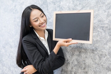Fototapeta na wymiar business woman holding blank black board,Blank black board template for insert text and graphic,empty black board mock up,selective focus.