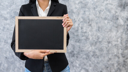 business woman holding blank black board,Blank black board template for insert text and graphic,empty black board mock up,selective focus.teacher holding black board in classroom concept.
