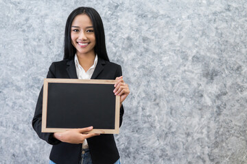 business woman holding blank black board,Blank black board template for insert text and graphic,empty black board mock up,selective focus.teacher holding black board in classroom concept.