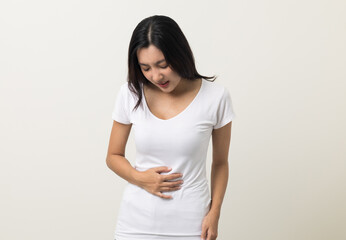 A woman had a stomach ache and gastritis. She put her hand on her stomach and squeezed it to relax and soothe. She is 25 years old and has menstrual cramps. Shot on isolated white background. © Chanakon