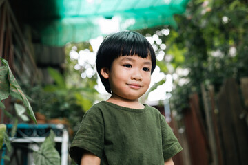Happy moment of little child playing in home garden. Asian boy love and caring the environment. The smile of a kid with a beautiful nature. Ecology concept.
