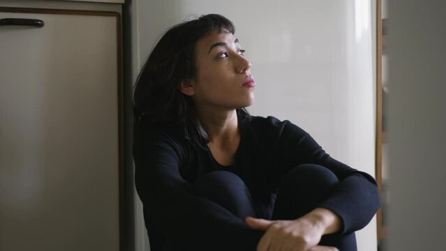 One anxious hispanic latina woman sitting on floor overwhelmed by problems