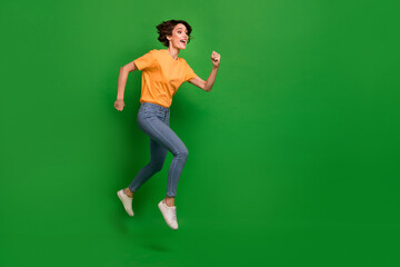 Fototapeta na wymiar Full size profile portrait of active energetic girl run jump look empty space isolated on green color background