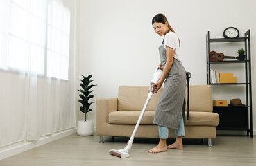 Housewife using vacuum cleaner on the floor. Wearing an apron to clean the living room at house....