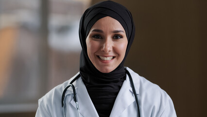 Happy muslim islamic woman doctor arabian girl female practitioner adviser in hijab look at webcam...