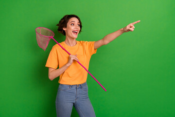 Portrait of excited positive girl arm hold butterfly net look direct finger empty space isolated on...
