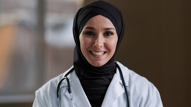 Happy muslim islamic woman doctor arabian girl female practitioner adviser in hijab look at webcam talk at distance video online consultation use distant teach medical service give professional advice