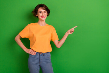 Photo of charming sweet young lady wear orange outfit smiling showing finger empty space isolated green color background