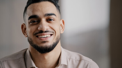 Obraz premium Dreaming arabic handsome young man agent worker deep in thoughts look away turn head at camera happy male human face friendly businessman millennial 20s guy smiling with toothy smile close up portrait