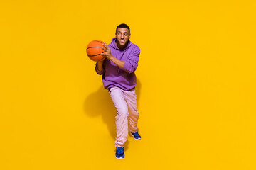 Full length body size view of attractive cheery sportive guy playing basketball isolated over vivid...