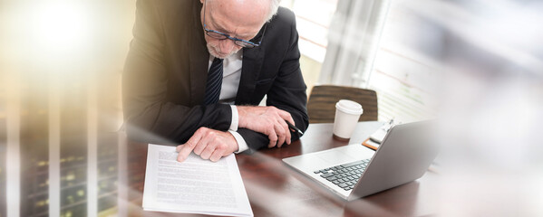 Senior businessman reading and checking document (lorem ipsum text used); multiple exposure
